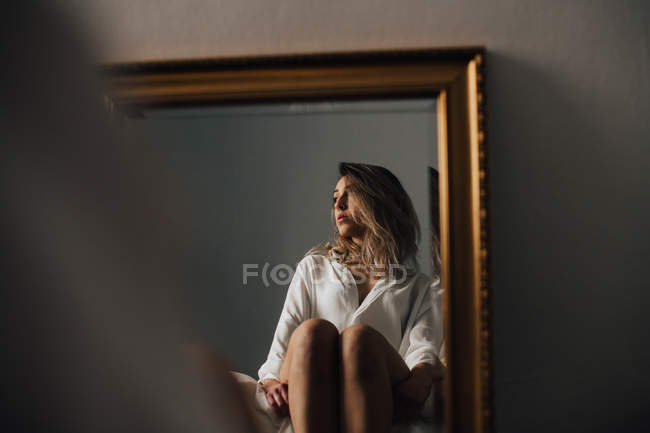 Spiegelbild einer Frau, die ihre Knie umarmt — Stockfoto