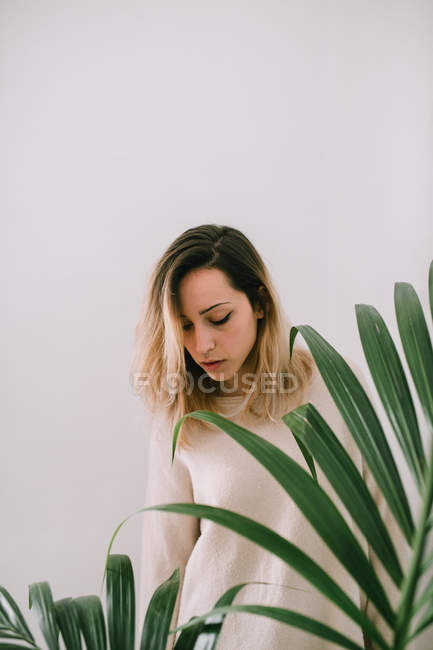 Сонная женщина рядом с растением — стоковое фото