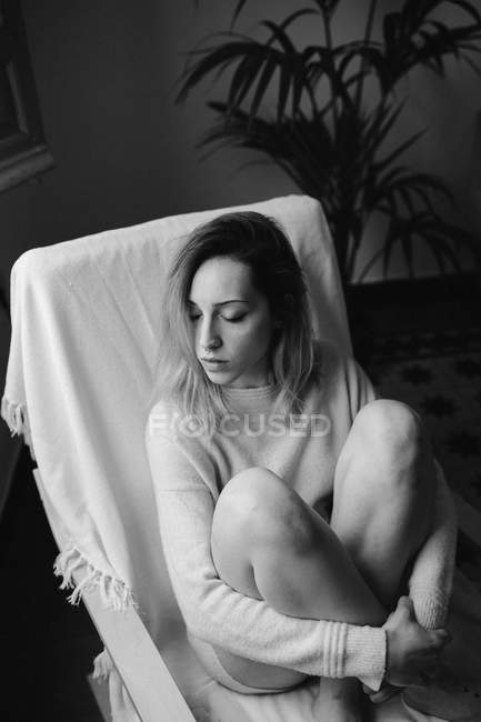 Jovem mulher sentada no sofá — Fotografia de Stock