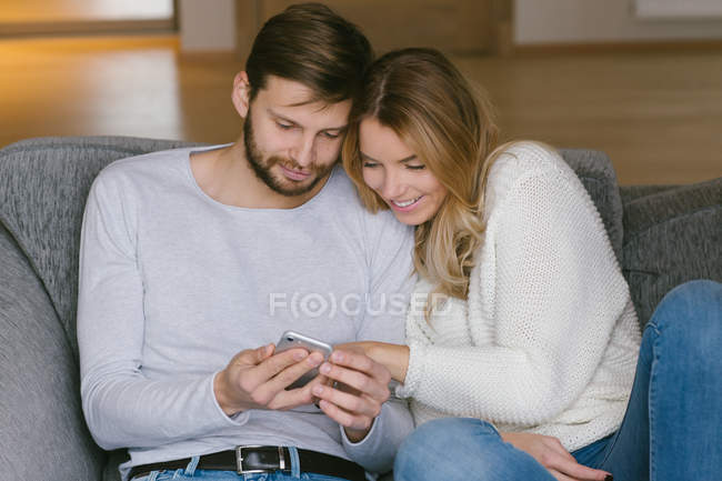 Couple browsing smartphone on sofa — Stock Photo