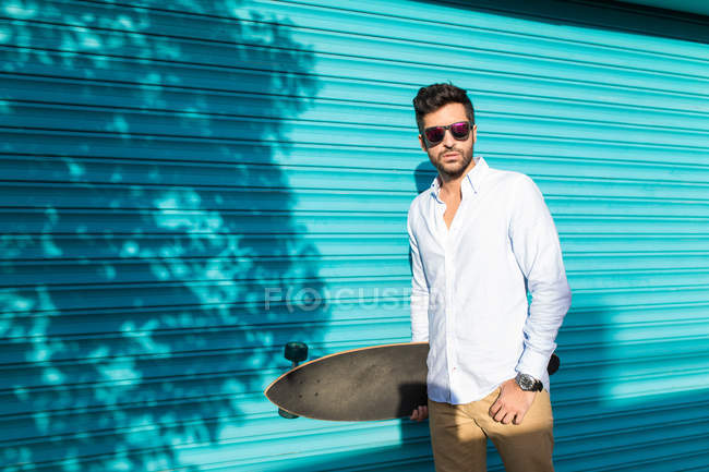 Young man in sunglasses holding skateboard — Stock Photo