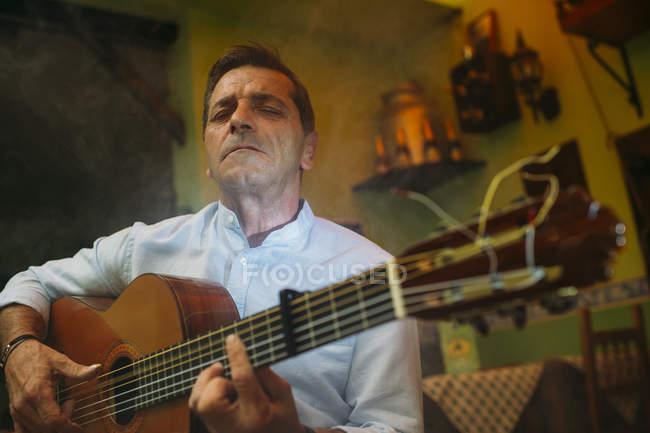 Portrait of elderly man playing guitar — Stock Photo