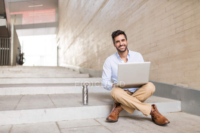 Man sitting on stairs with notebook — Stock Photo