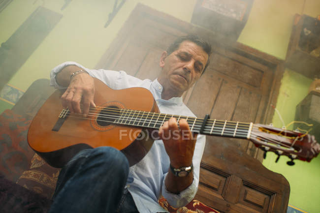 Portrait of elderly man playing guitar — Stock Photo