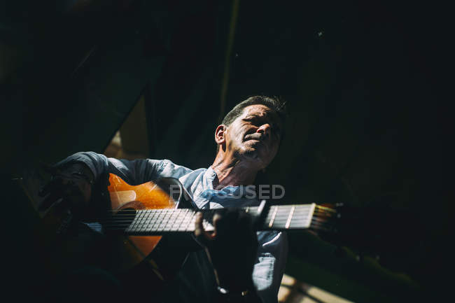 Пожилой человек играет на гитаре — стоковое фото
