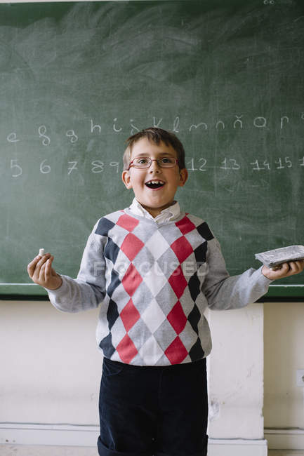 Little kid standing at blackboard in classroom — Stock Photo