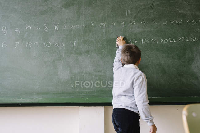Little kid standing at blackboard — Stock Photo