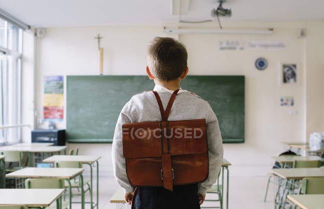 Menino com saco escolar em sala de aula — Fotografia de Stock