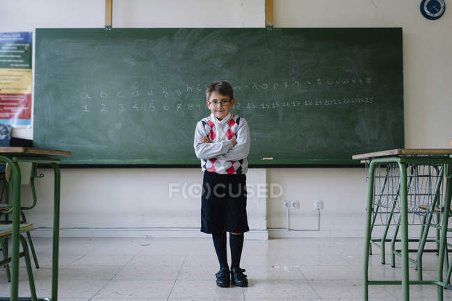 Criança em pé no quadro negro na sala de aula — Fotografia de Stock