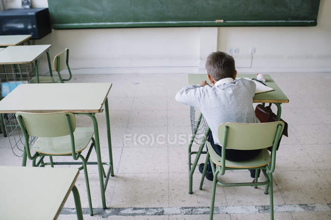Écolier au bureau en classe — Photo de stock