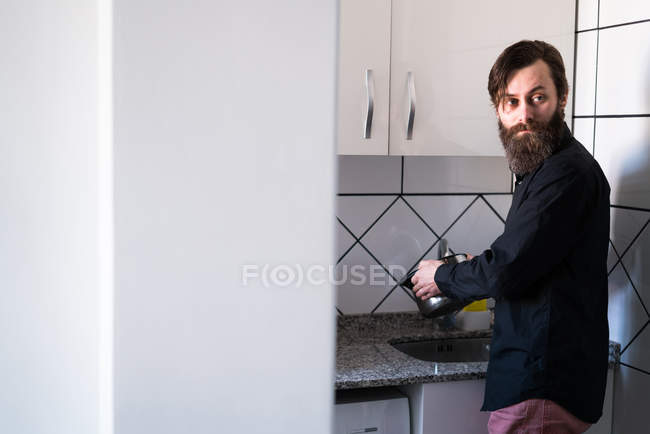 Бородатый мужчина моет посуду — стоковое фото