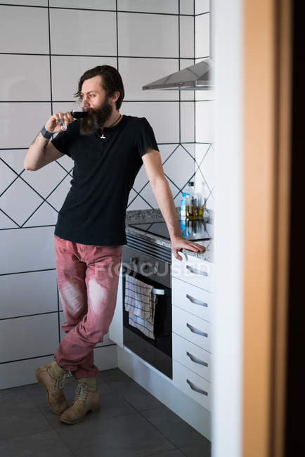 Hombre bebiendo vino en la cocina - foto de stock