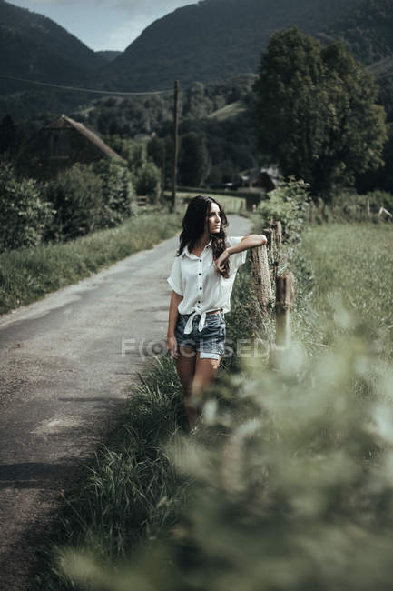 Jolie femme à la clôture rurale — Photo de stock