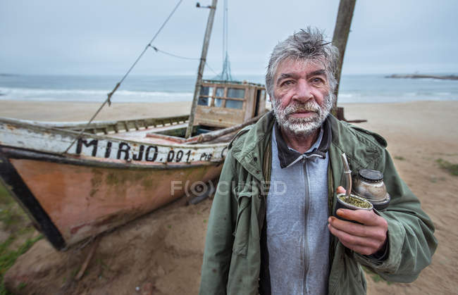 Старый рыбак стоит на пляже — стоковое фото