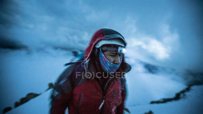Anonymous person in extremely warm clothing and with trekking equipment among snows in bad weather. — Stock Photo