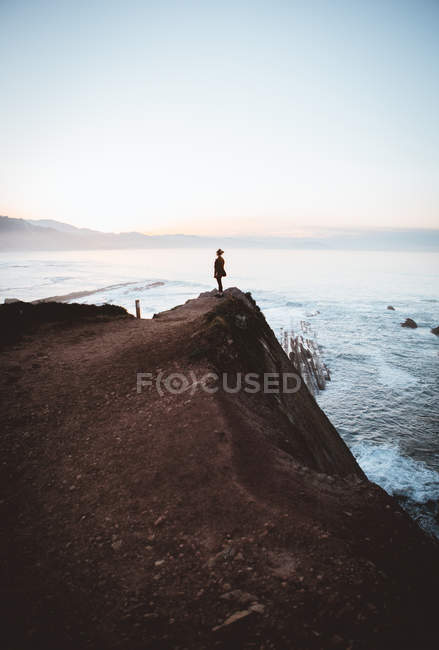 Человек на скале на берегу моря — стоковое фото