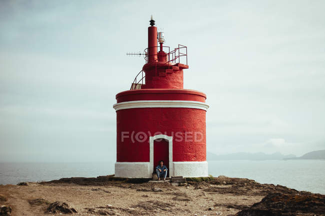 Tourist and lighthouse on coastline — Stock Photo