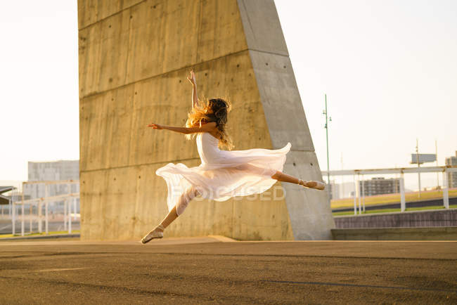 Вид сбоку на танцующего молодого артиста балета на городской сцене — стоковое фото