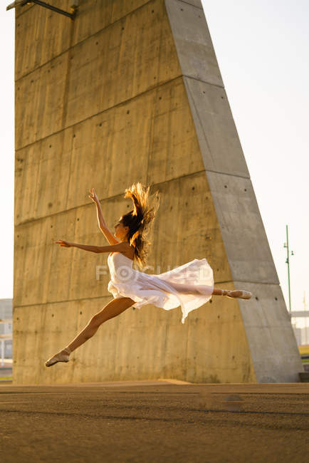 Vista lateral de bailarina de ballet bailando en la escena urbana - foto de stock