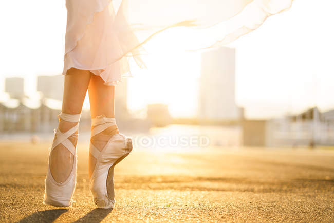 Close up view of unrecognizable ballerina dancing in ballet shoes and at sunrise. — Stock Photo