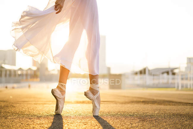 Unterteil einer unkenntlichen Ballerina, die in Ballettschuhen und bei Sonnenaufgang tanzt. — Stockfoto