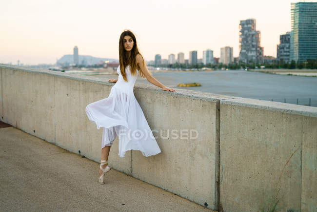 Brunette ballerina girl leaning on stone handrail and looking aside — Stock Photo