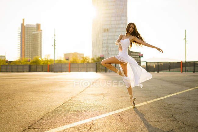 Чуттєва балерина танцює на сонячно освітленій асфальтовій площі — стокове фото