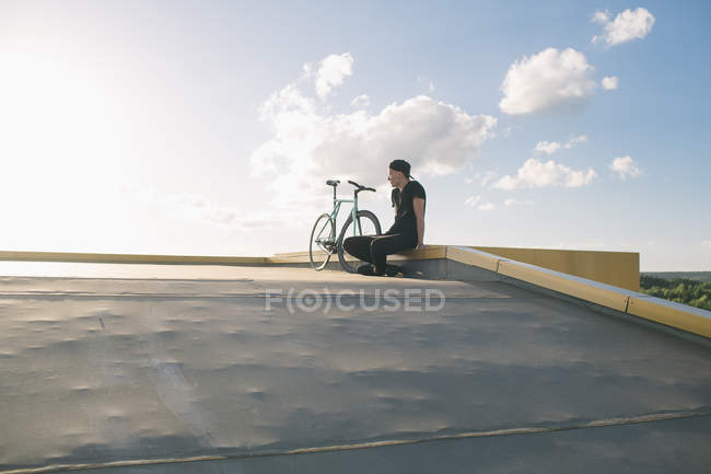 Мальчик в черном сидит рядом с велосипедом — стоковое фото