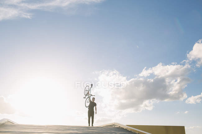 Silueta de jinete con bicicleta por encima de la cabeza - foto de stock