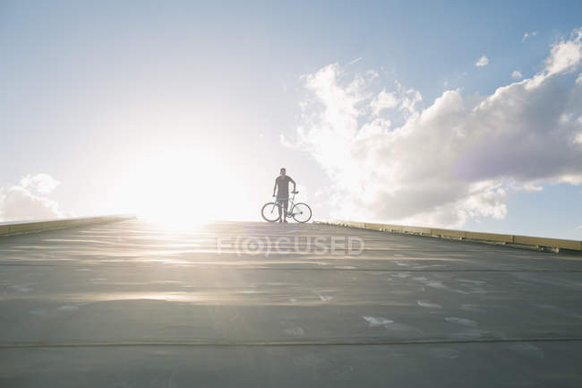 Silhoutte di maschio in piedi con bici — Foto stock