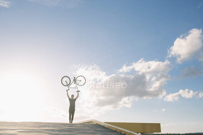 Silhouette di ragazzo con bici sopra la testa — Foto stock