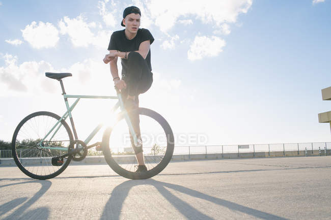 Ciclista con pierna sobre rueda de bicicleta - foto de stock