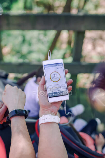 Vista acima do smartphone com taxa de pulso mostrando atividade na mão feminina.Bokeh — Fotografia de Stock
