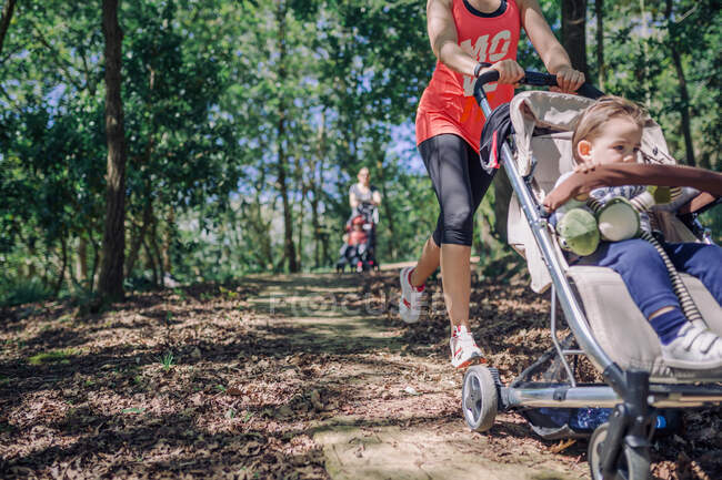 Неузнаваемые мамы занимаются спортом с колясками в парке — стоковое фото