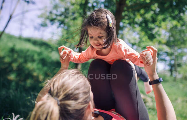 Unerkennbare Mutter mit ihrer Tochter im Park vor hellem Bokeh-Hintergrund — Stockfoto