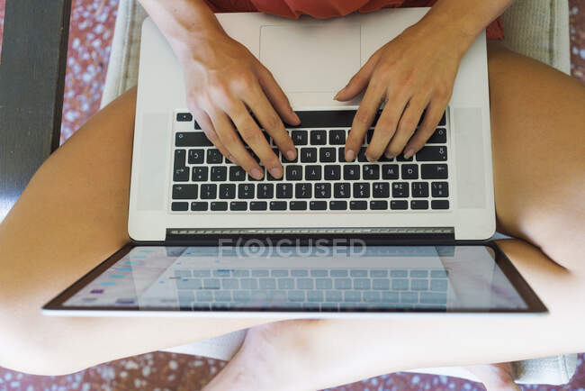 Über der Ansicht einer unkenntlichen jungen Frau, die barfuß im Sessel sitzt und am Laptop arbeitet — Stockfoto