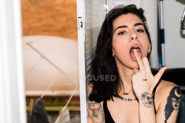 Mujer con la boca abierta mostrando el dedo medio - foto de stock