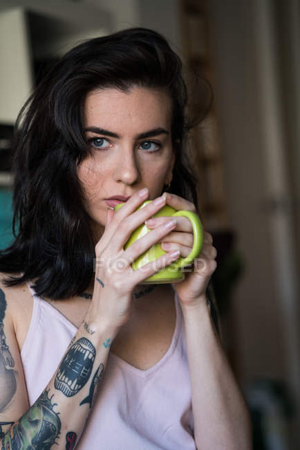 Giovane bella bruna tatuata che tiene la tazza — Foto stock