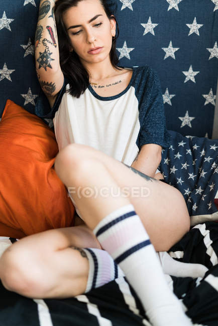 Femme tatouée en chemise sur le lit — Photo de stock
