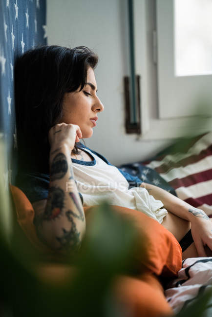 Sensuelle jeune femme tatouée sur le lit — Photo de stock
