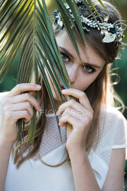 Fille posant derrière la feuille de palme . — Photo de stock