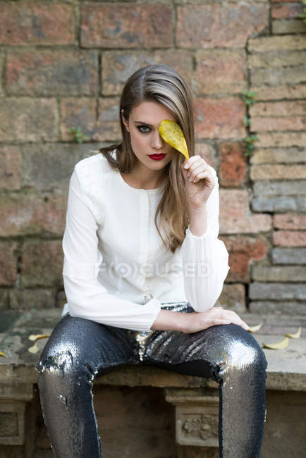Жінка в гламурному вбранні позує з листям — стокове фото