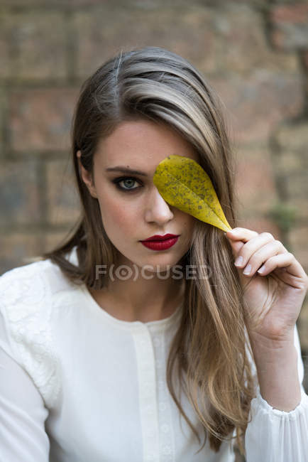 Femme en tenue glamour posant avec des feuilles — Photo de stock