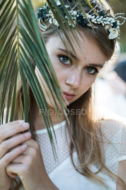 Tendre fille derrière la feuille de palme — Photo de stock