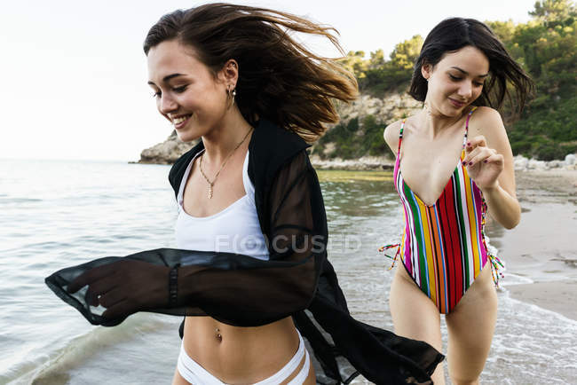 Cheerful girls running on beach — Stock Photo
