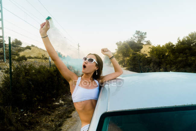 Mädchen posiert mit Rauchbombe im Auto — Stockfoto