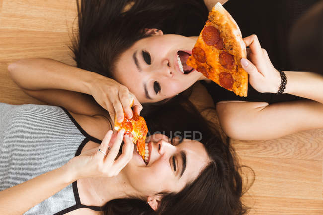 Молоді жінки кусають піцу — стокове фото