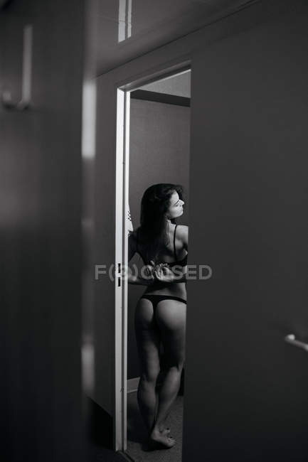 Rear view of sensual brunette woman in black lingerie undressing. — Stock Photo