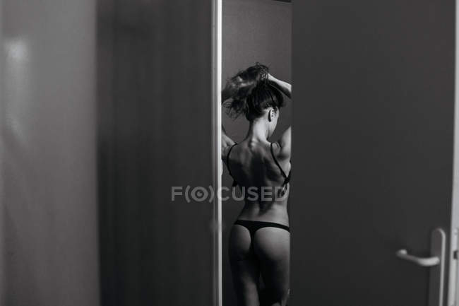 Rear view of sensual woman in black lingerie undressing. — Stock Photo