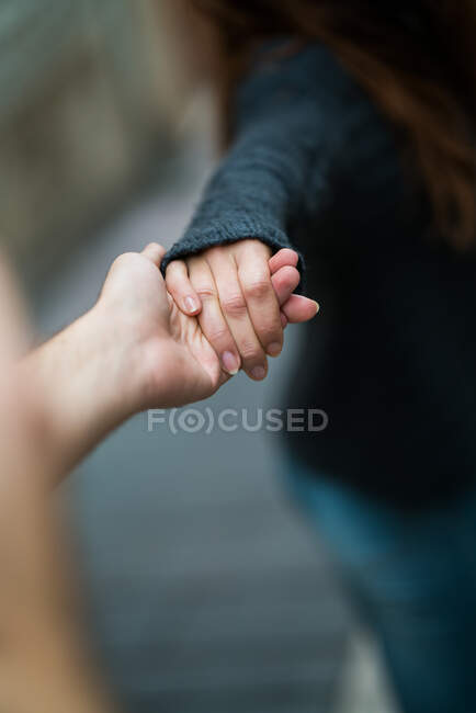 Jemand hält Frau in schwarzem Pullover mit der Hand auf verschwommenem Hintergrund. — Stockfoto